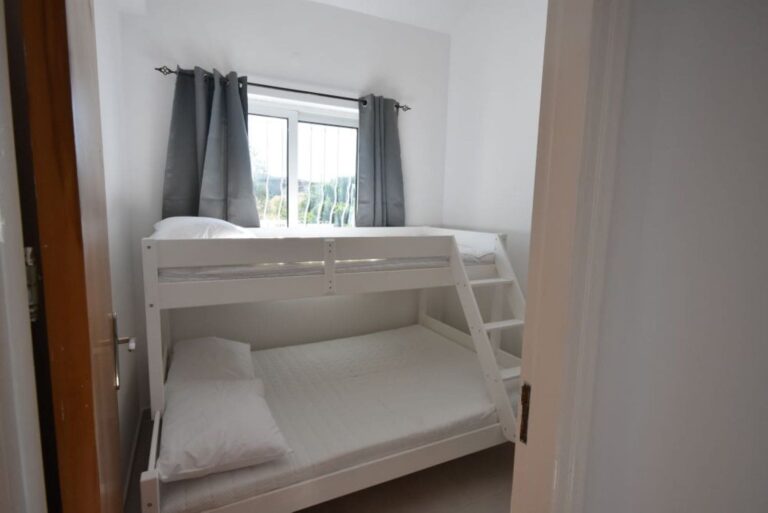 Fourth bedroom at Sofia Villa with white bunk beds, fresh bedding, and a window with natural light.